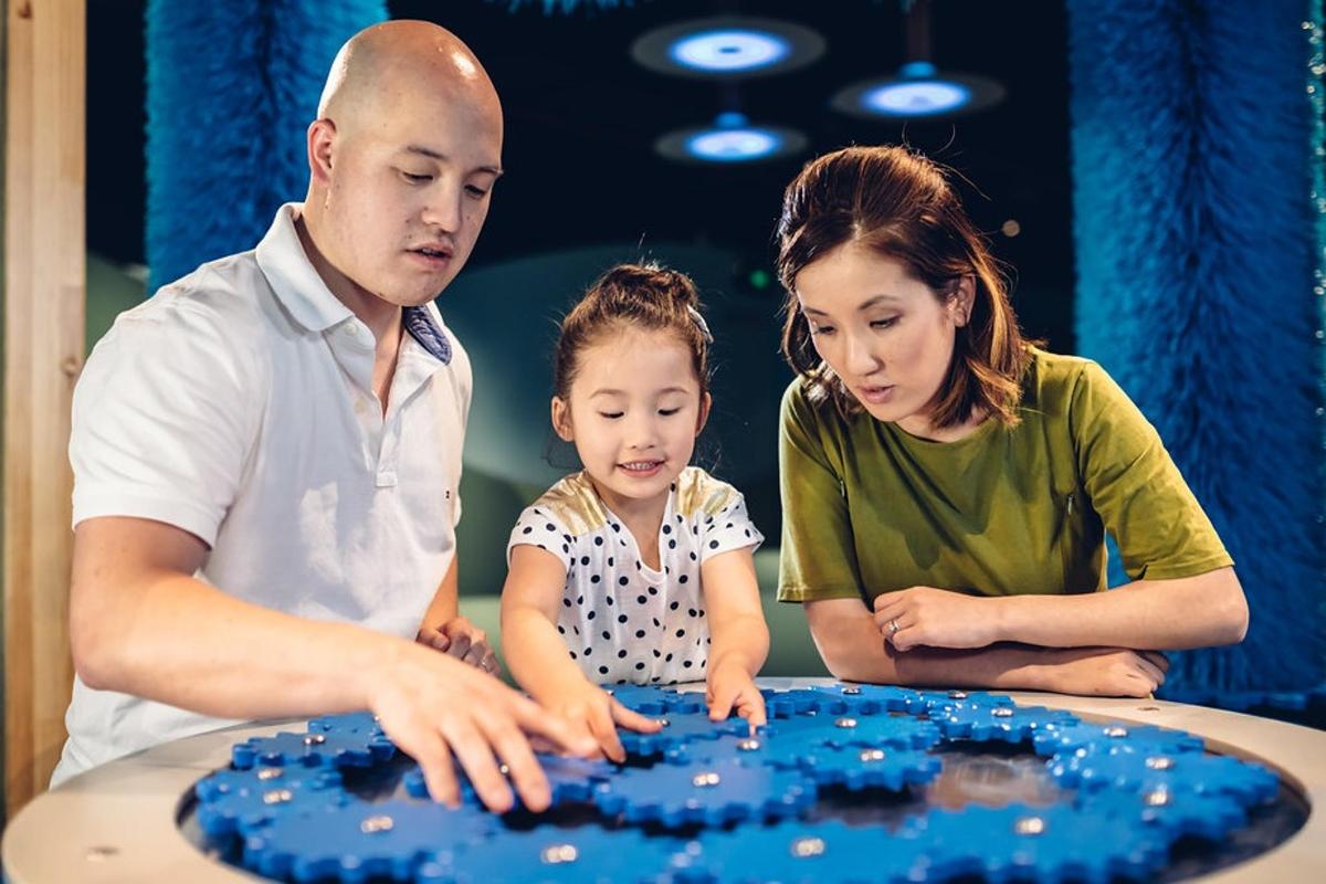 một người đàn ông, một người phụ nữ và một cô bé đang nhìn vào một cái bàn
