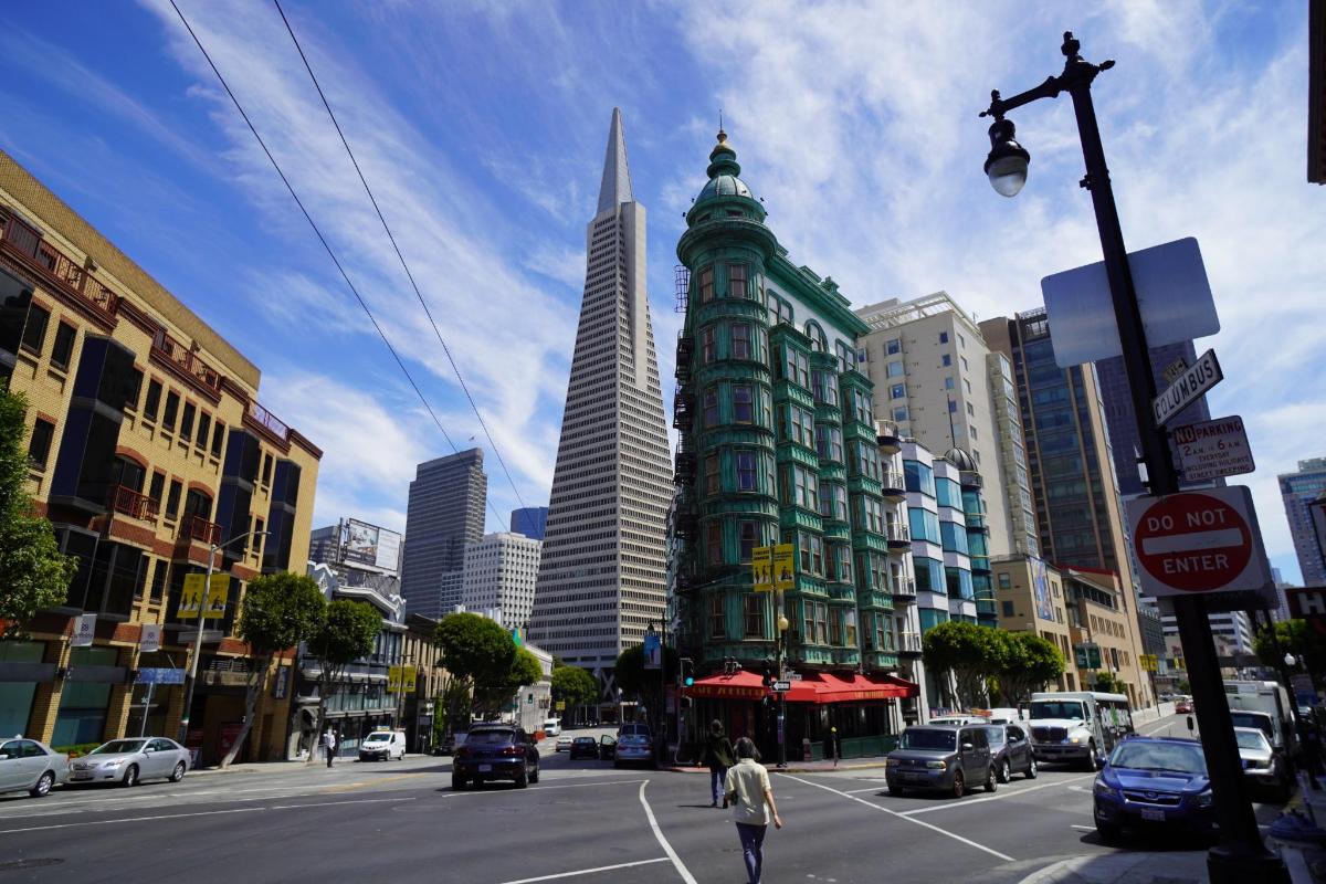 Una calle de la ciudad con un alto edificio verde con un rascacielos