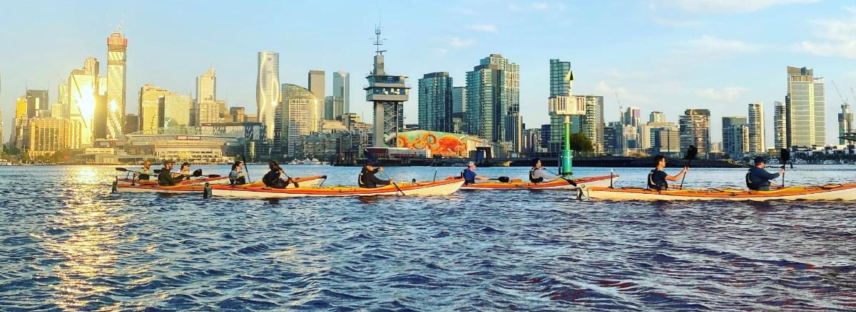 a group of people on boats in the water with a city