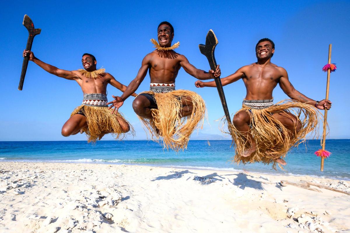 three men jumping in the air on the beach