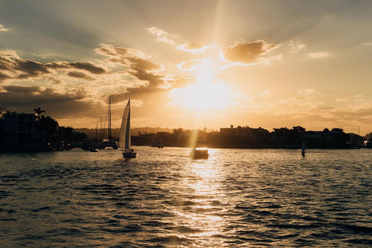 a sailboat on the water with the sun setting