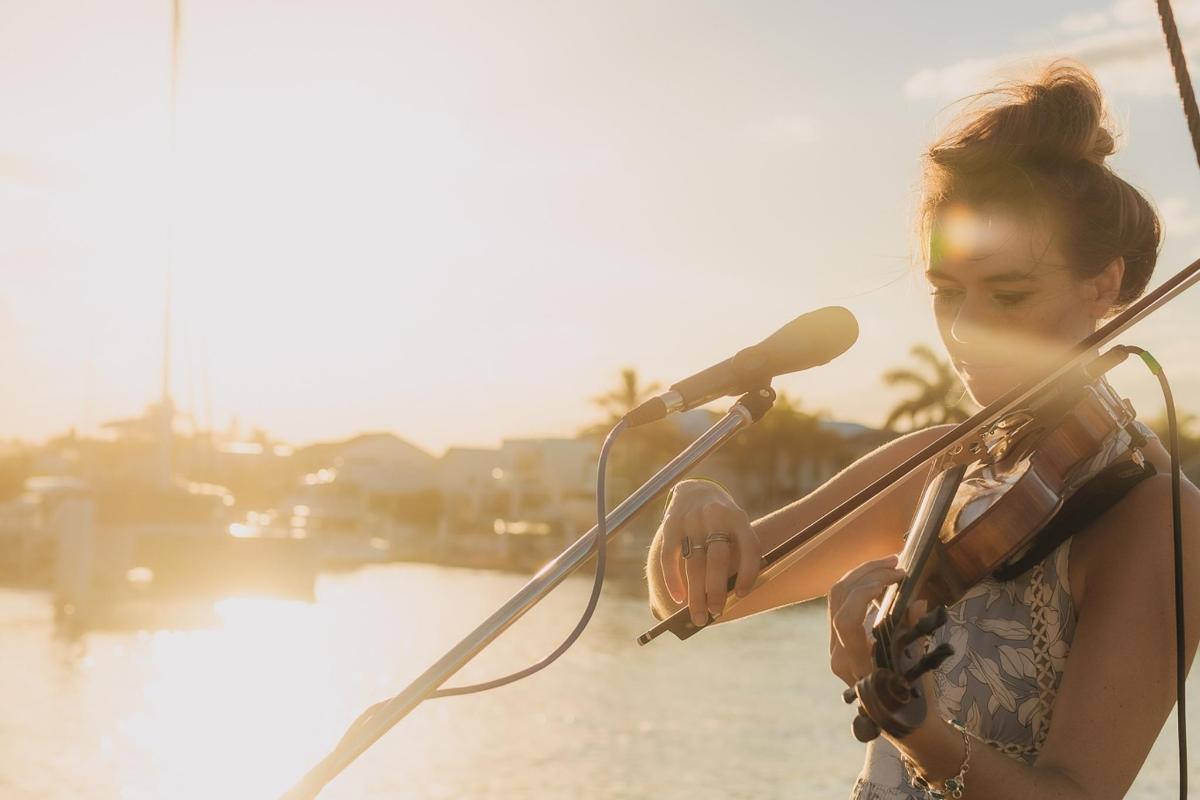 a woman playing a violin next to a microphone