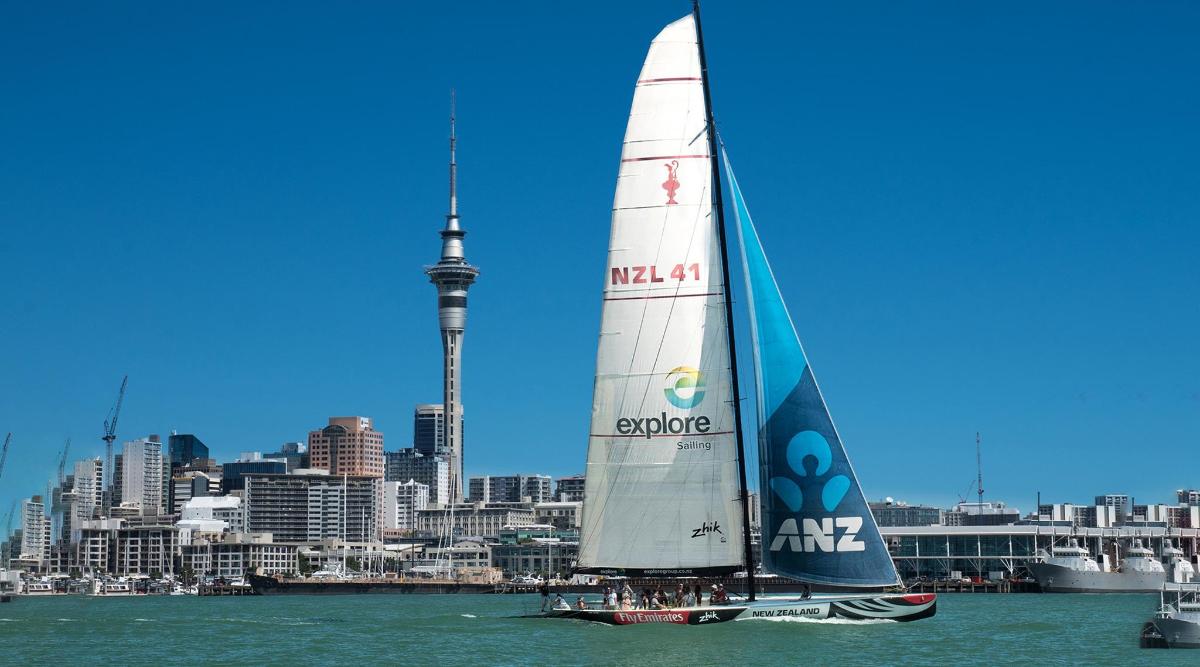a sail boat in the water with auckland city in the background