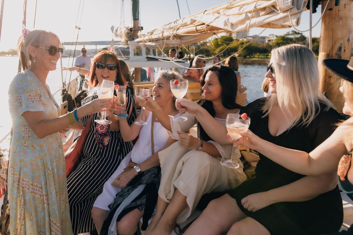 a group of women sitting on a boat drinking wine