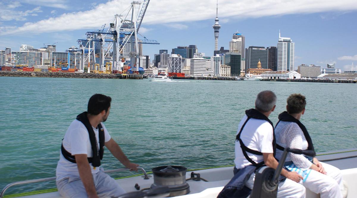 three men on a boat in the water with a city
