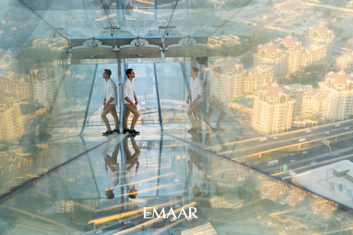 three men walking on the glass floor of an observation tower