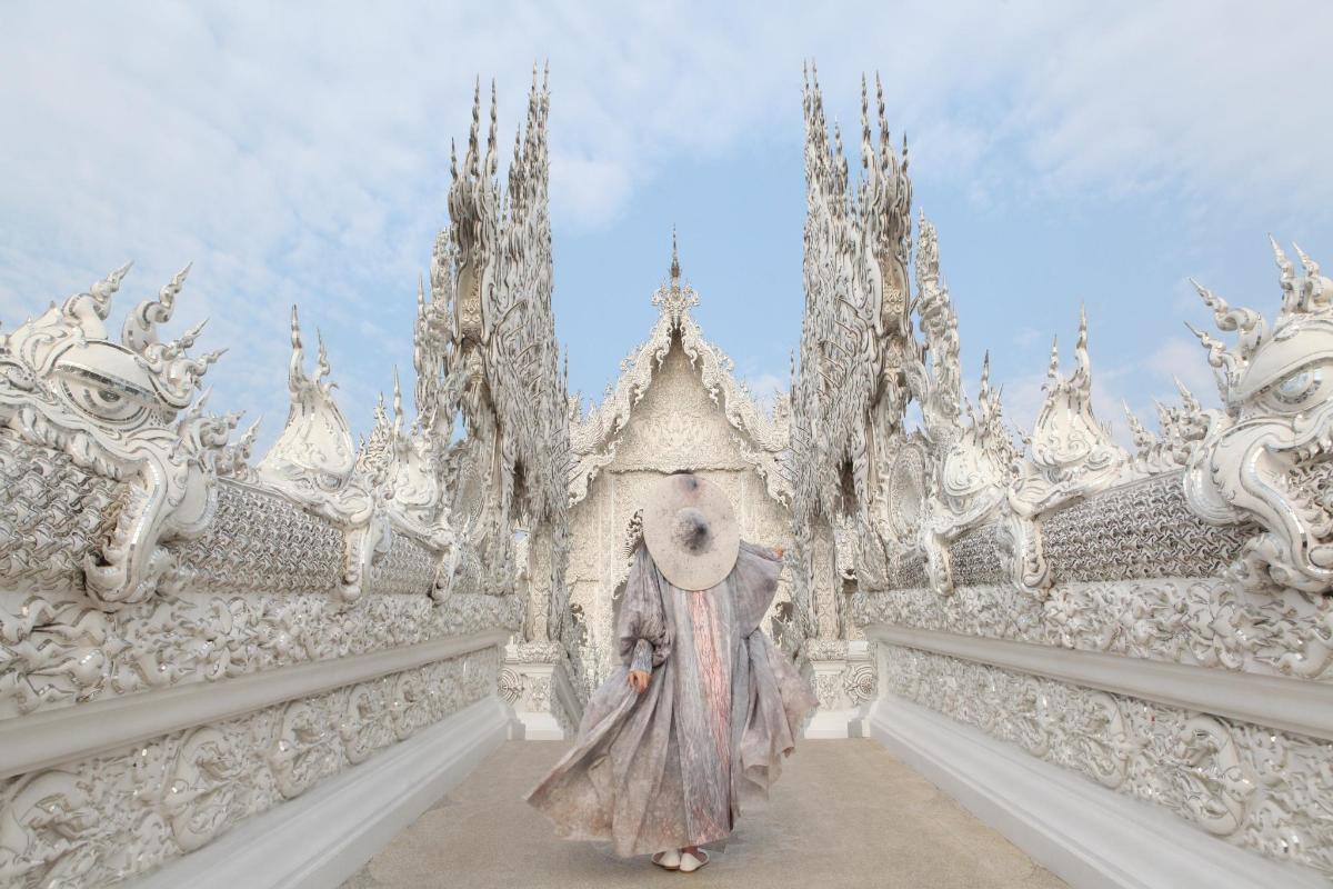 a woman in a dress stands in front of a white temple