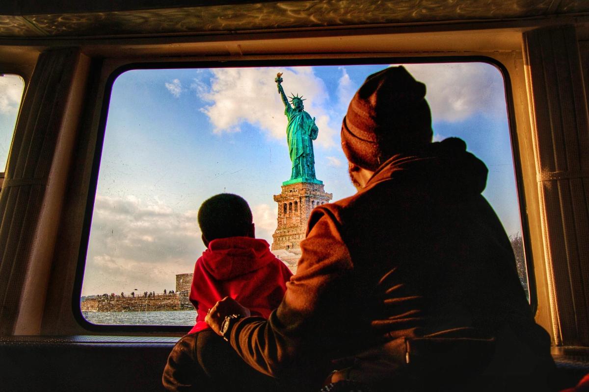 Una mujer y un niño en un tren mirando la estatua de la libertad