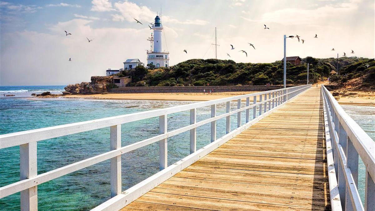 un passeig de fusta que condueix a un far a la platja