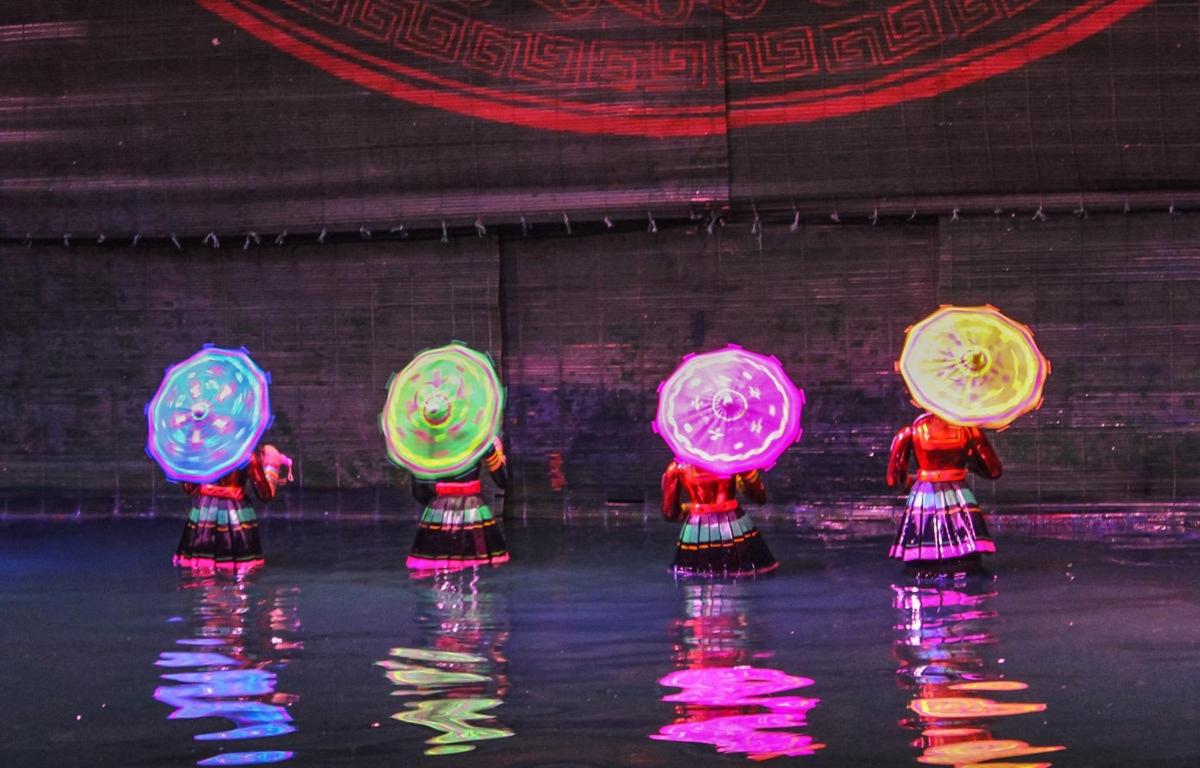a group of people standing in the water with umbrellas