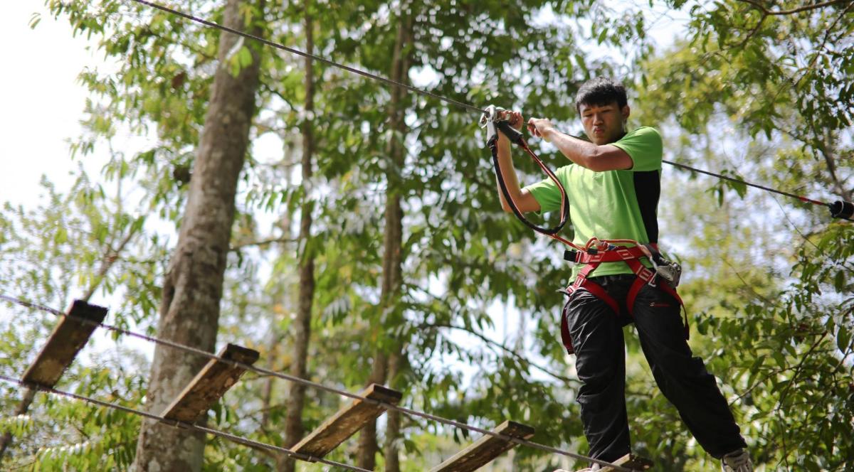 a man on a zip line in the forest