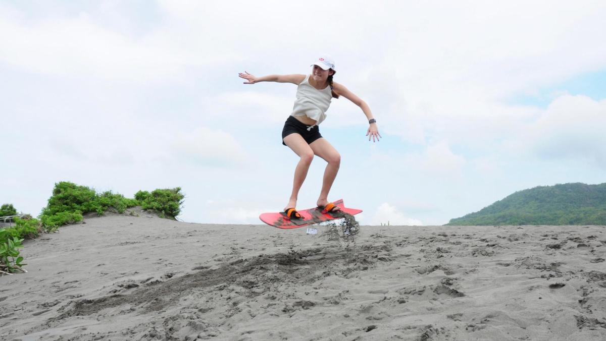 una dona muntant una taula de surf a la platja