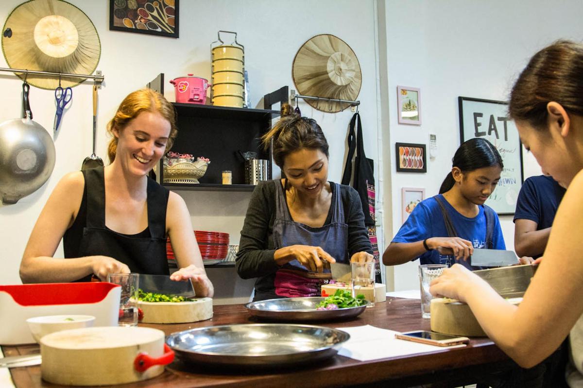 a group of women standing around a table preparing food