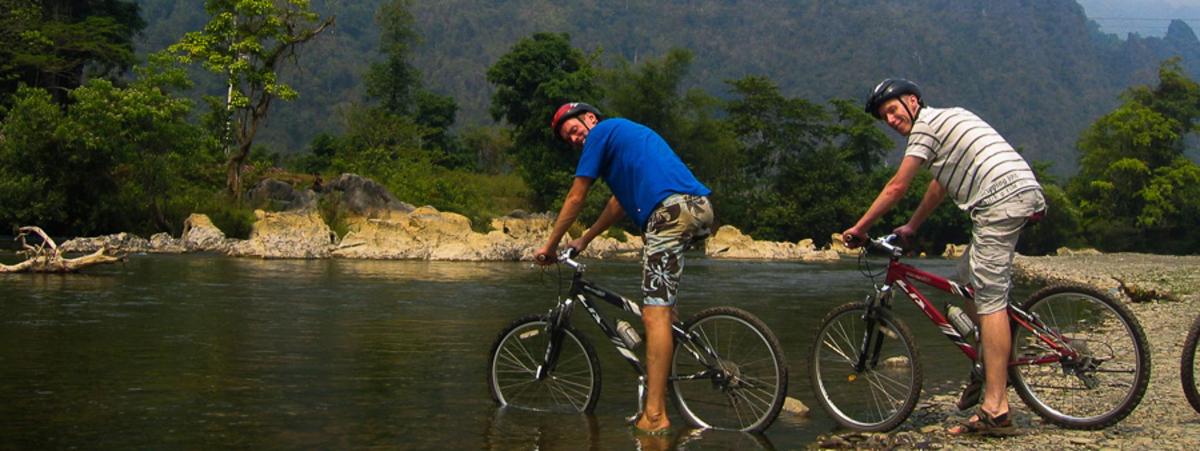 two men on bikes crossing a river