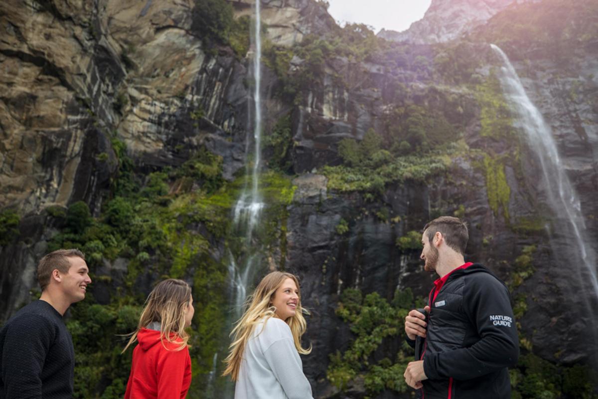 a group of people standing in front of a waterfall