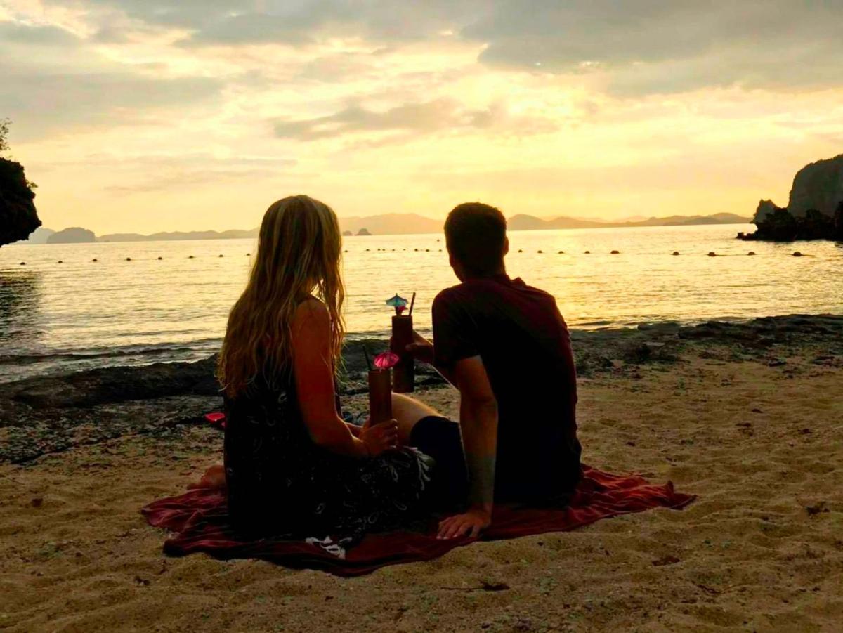 a couple sitting on the beach watching the sunset