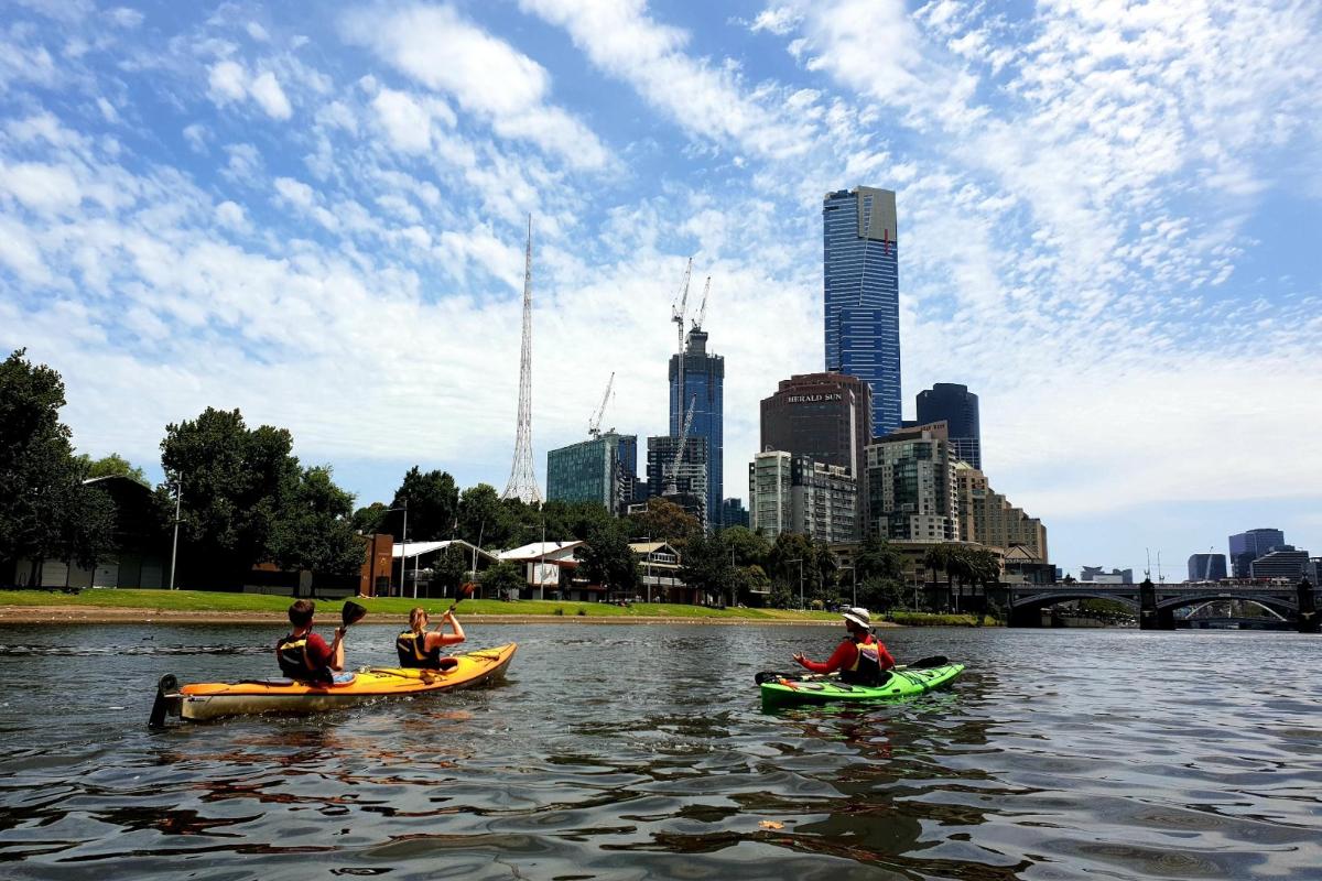 Tres personas en kayaks en el agua en una ciudad