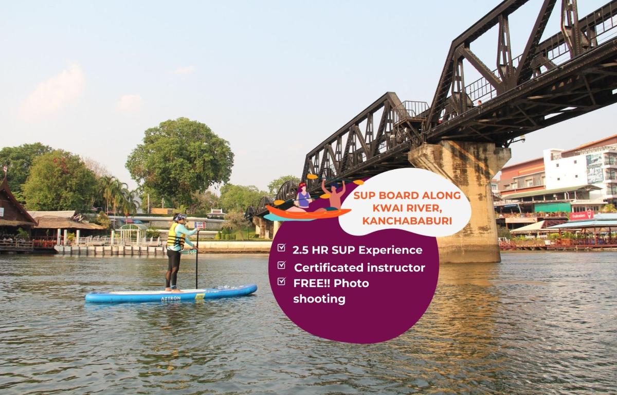 a man on a paddle board in the water under a bridge