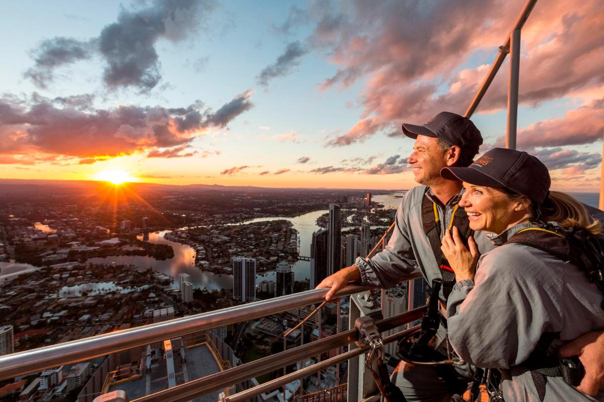 two people standing on top of a tower looking at the sunset