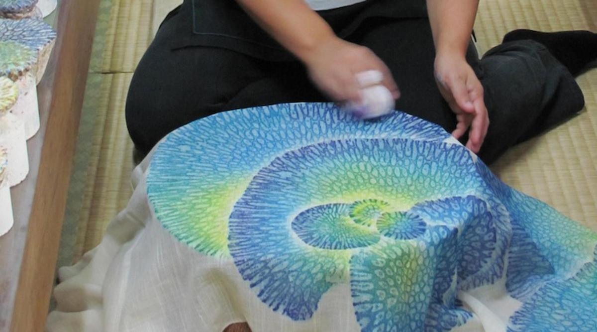 a person sitting on the floor holding a peacock pillow
