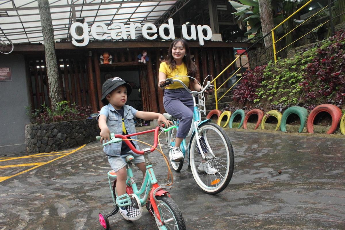Una niña y un niño andan en bicicleta frente a una tienda