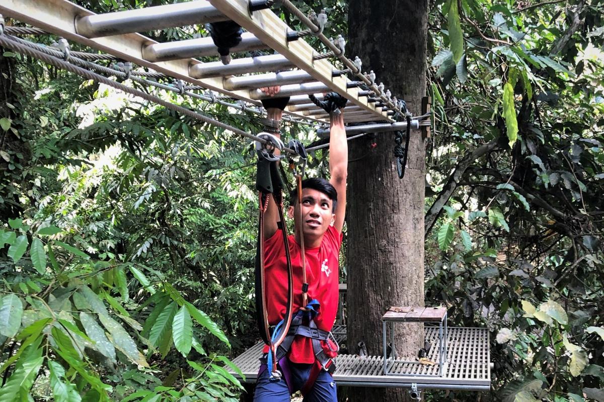 a boy is hanging on a rope swing in the jungle