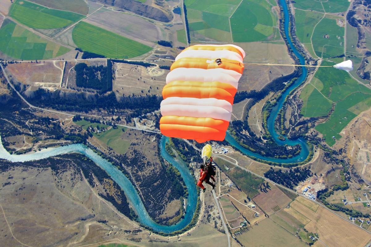 oranžový a bílý horkovzdušný balón letící nad řekou