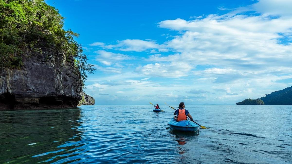 Dos personas en kayaks en el agua cerca de un acantilado