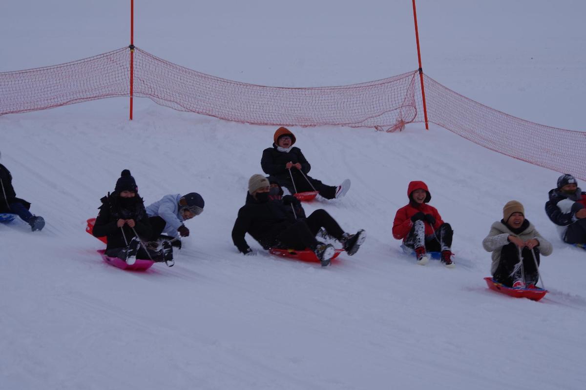 skupina lidí sedících ve sněhu na snowboardech