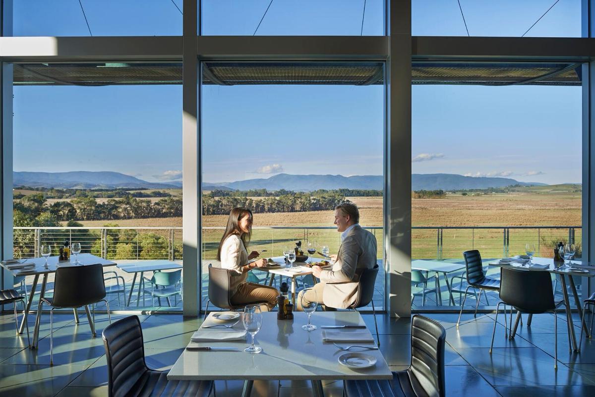 two people sitting at tables in a restaurant with large windows