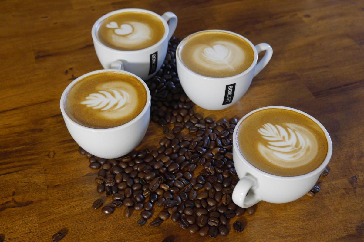 quattro tazze di caffè su un tavolo con chicchi di caffè