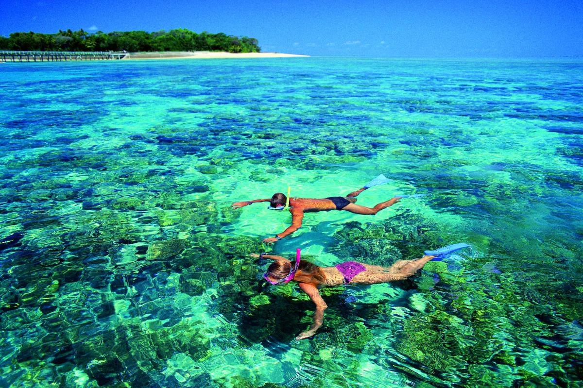 two people swimming in the clear blue ocean