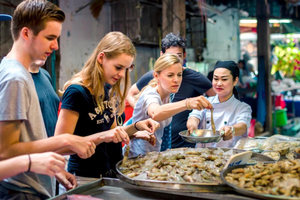 a group of people standing around a table with pizzas