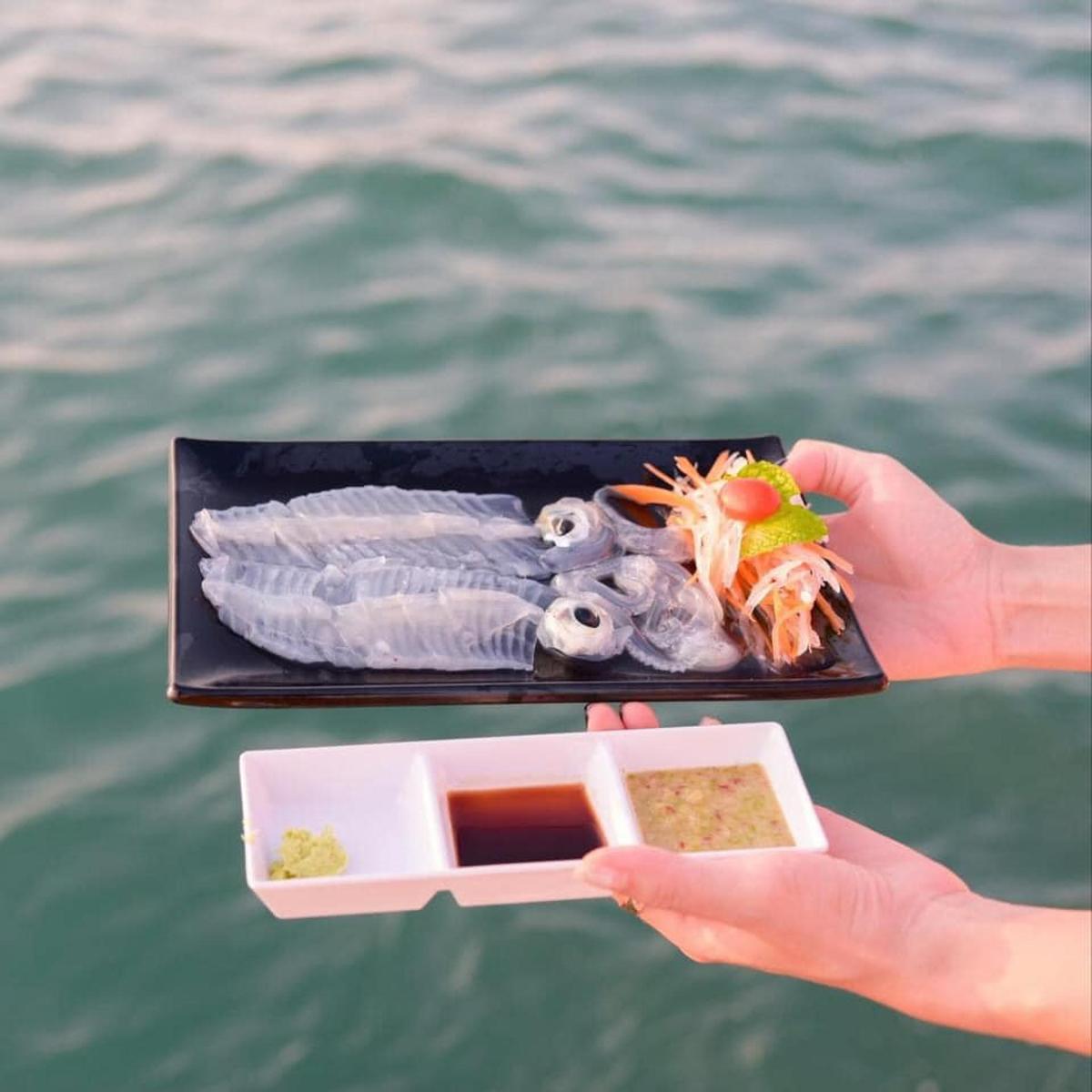 a person holding a tray of food with a plate of seafood