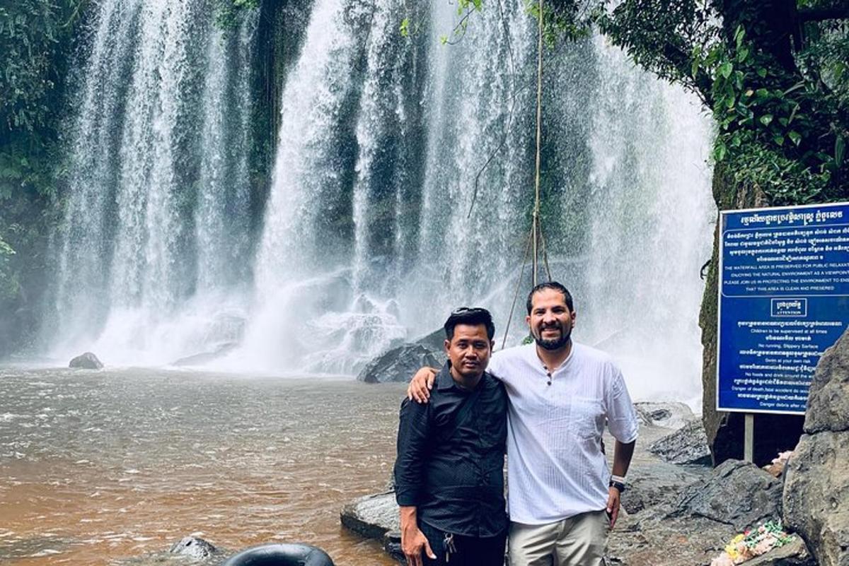 two men standing in front of a waterfall