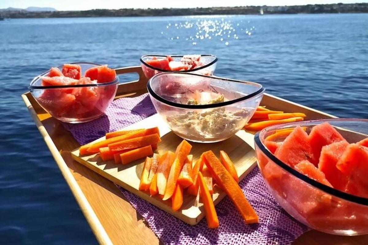 uma bandeja com frutas e vegetais em uma mesa ao lado da água
