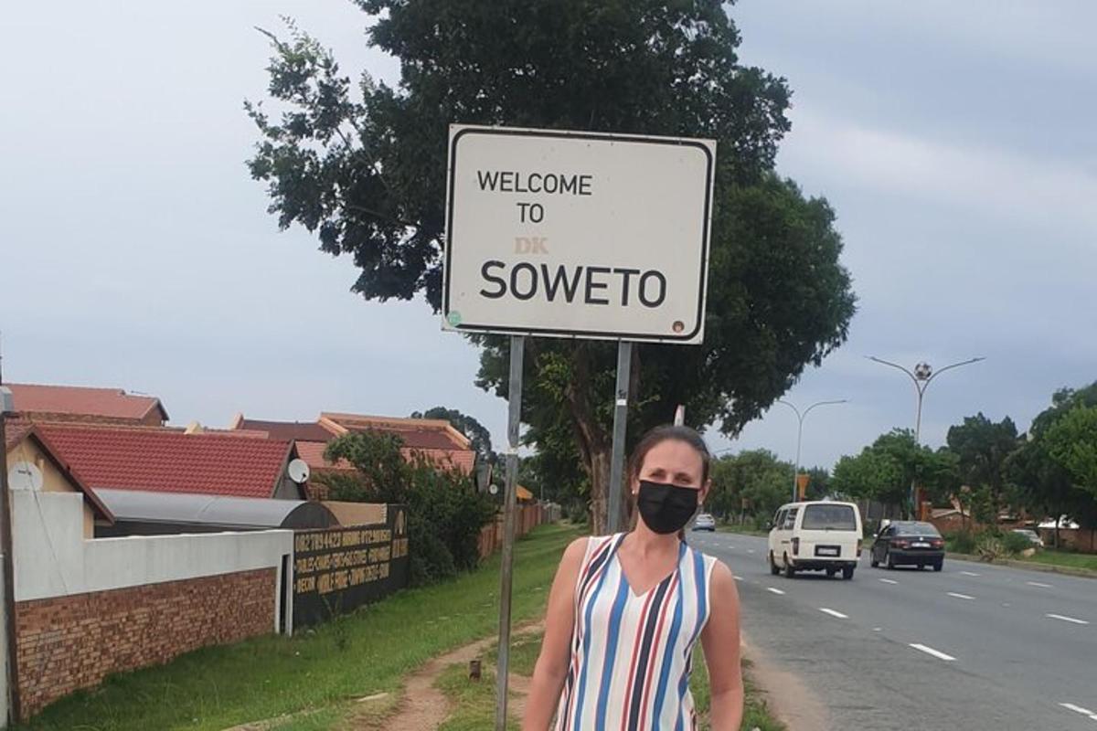 um homem usando uma máscara em pé na frente de uma placa