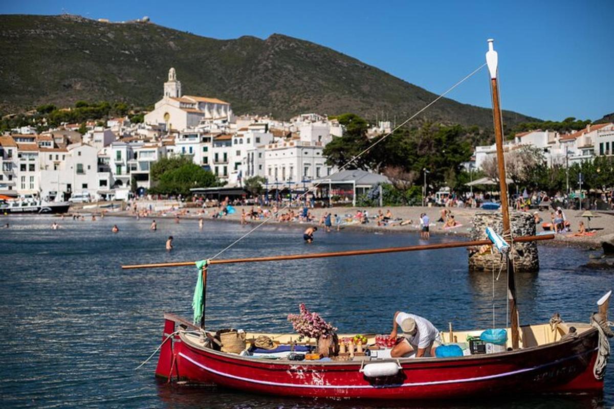 egy piros hajó ül a vízben a strand közelében