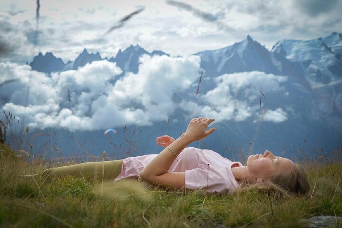a woman laying in a field with her hands in the air