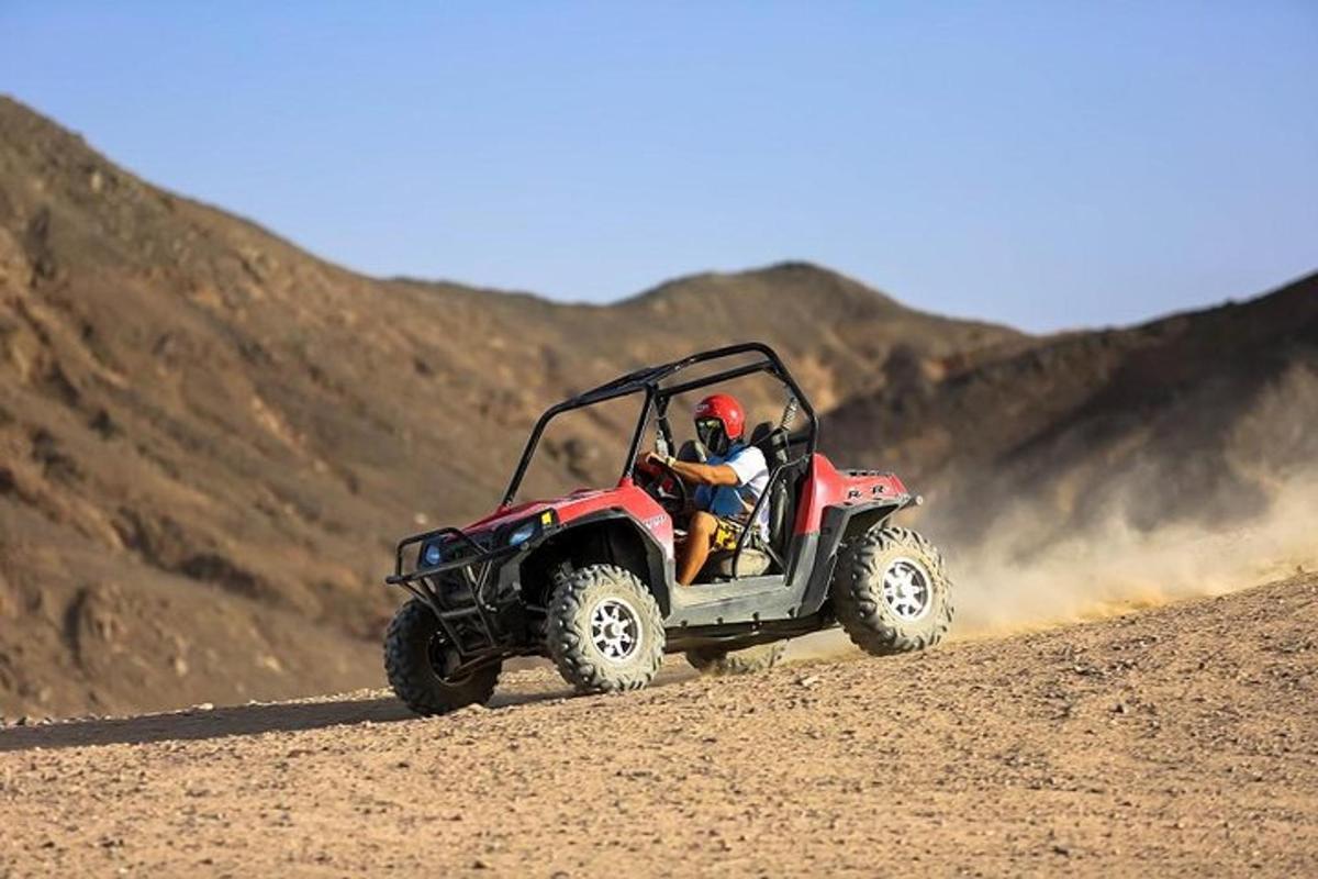 çölde kırmızı bir ATV'ye binen bir kişi