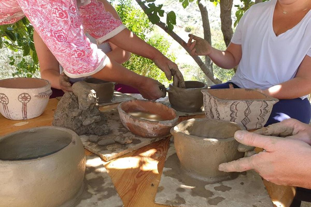 um grupo de pessoas fazendo potes em uma mesa