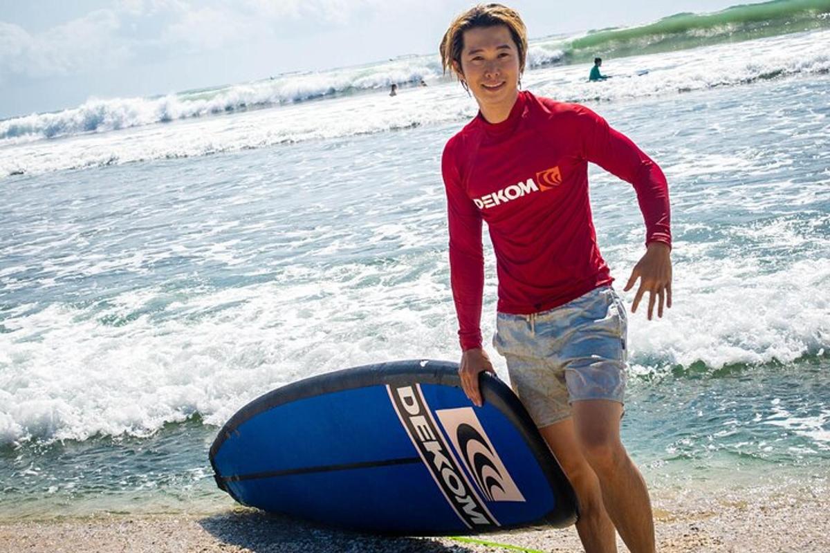 a man standing next to a surfboard on the beach