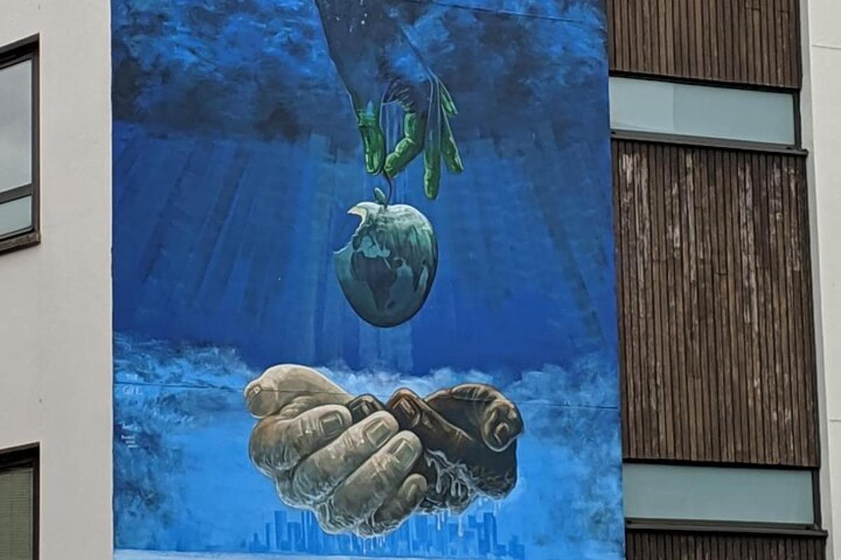 nástěnná malba na boční straně budovy s rukou držící ovoce