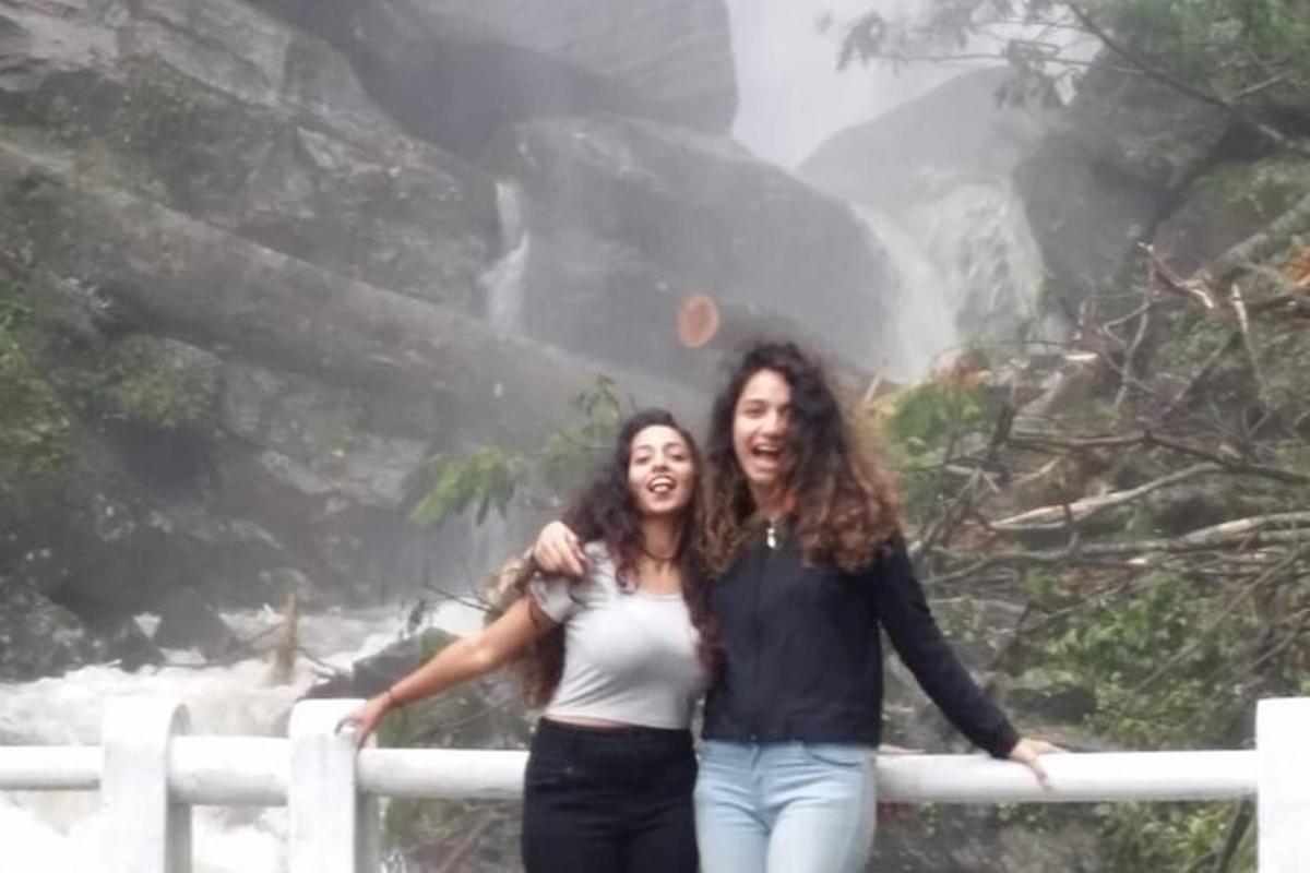 two women posing for a picture in front of a waterfall
