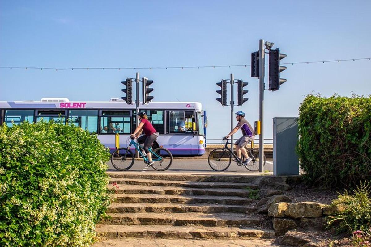 two people riding bikes in front of a bus