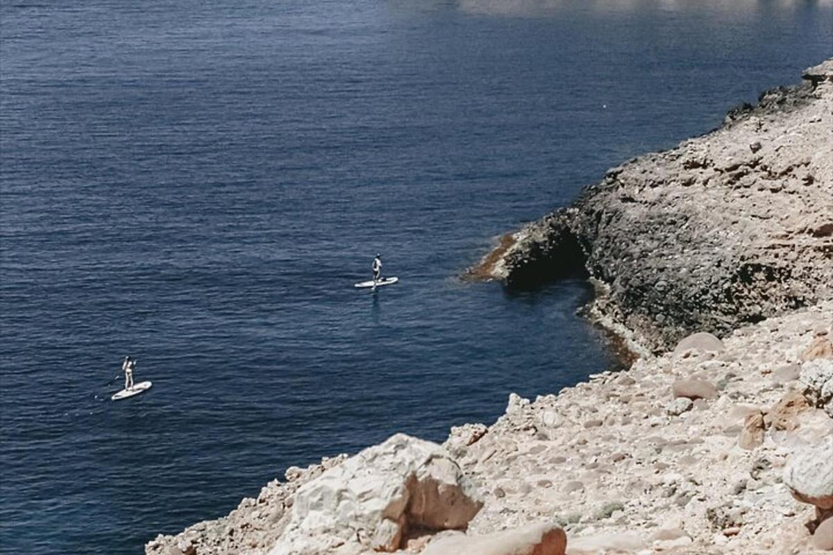 two boats in the water next to a rocky shore