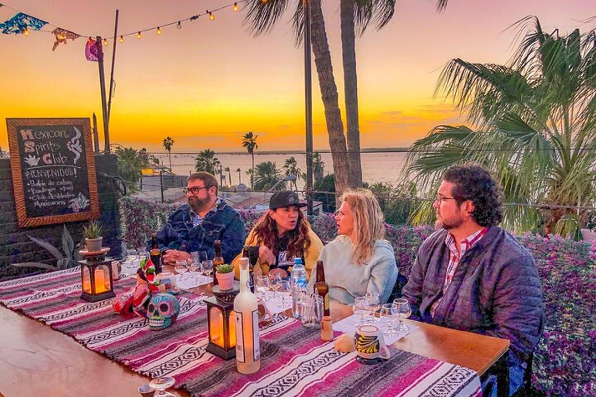 een groep mensen die aan een tafel zitten met het strand op de achtergrond
