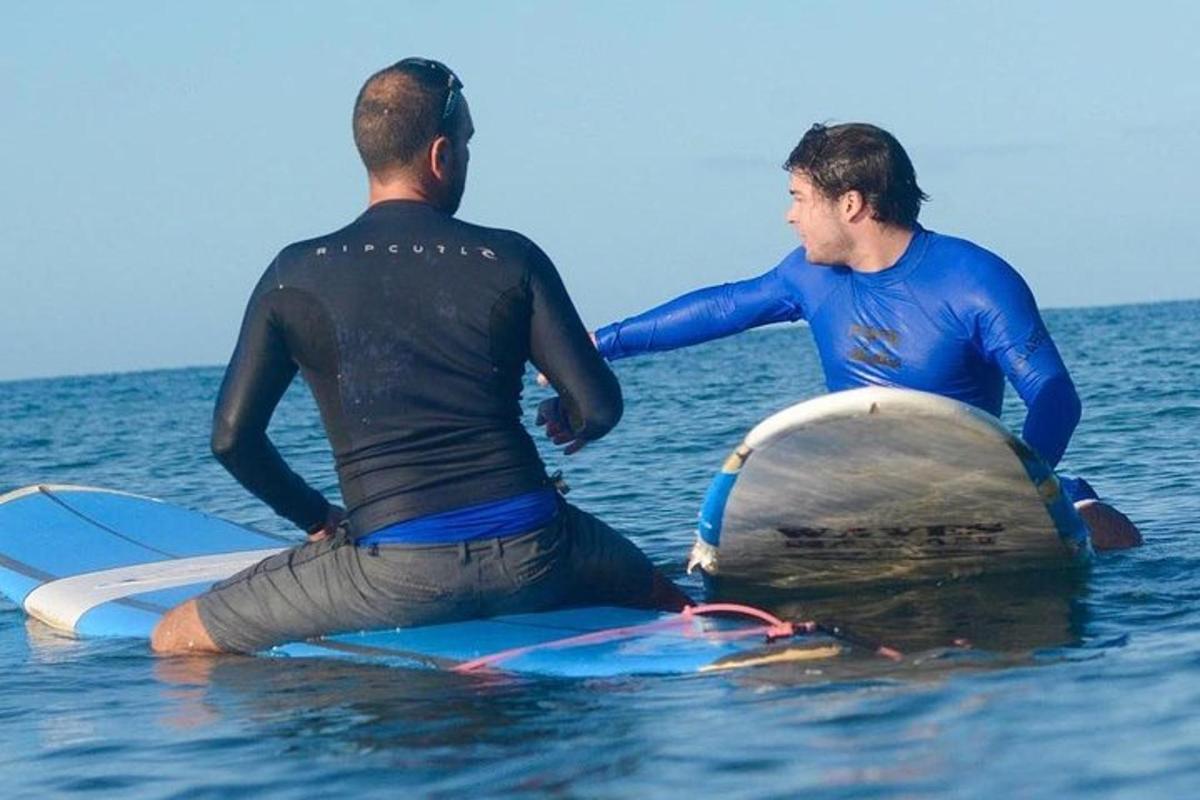 due uomini seduti su tavole da surf in acqua