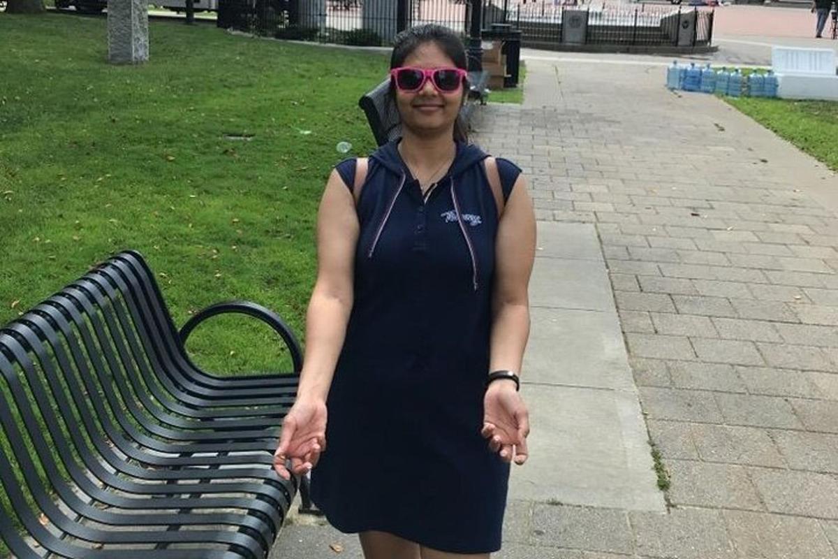 a woman in a black dress standing next to a bench