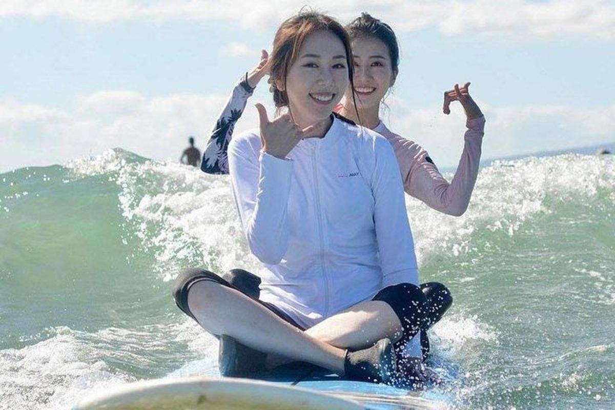 Dos chicas sentadas en una tabla de surf en el océano
